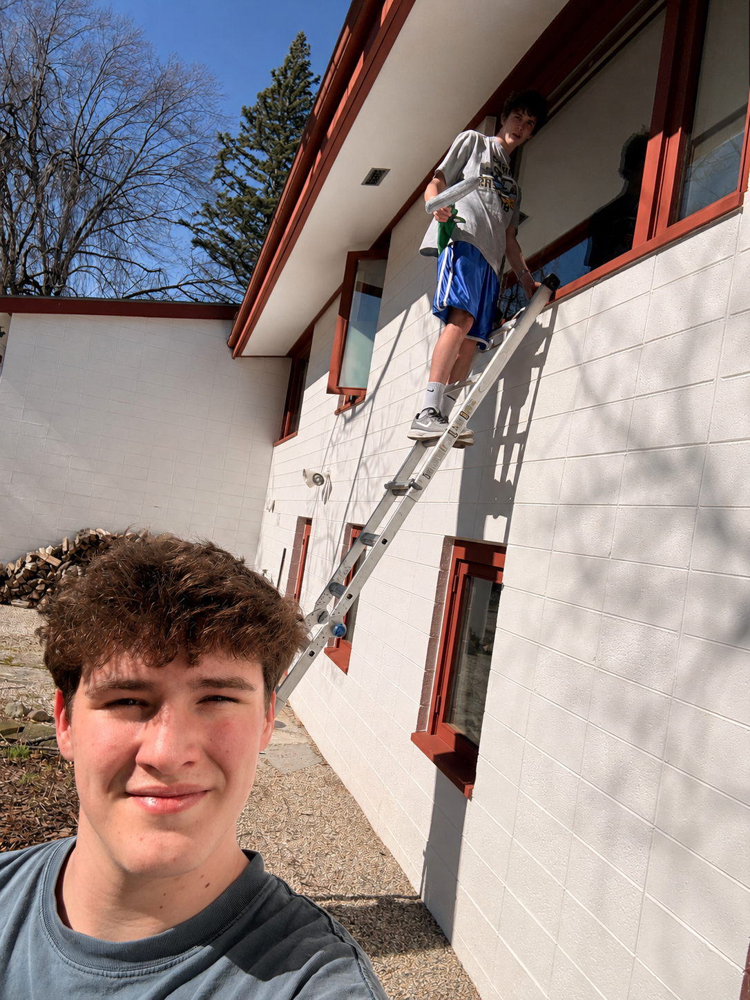 Oliver Karbowski and Jackson Larson on the job — washing windows on a ladder